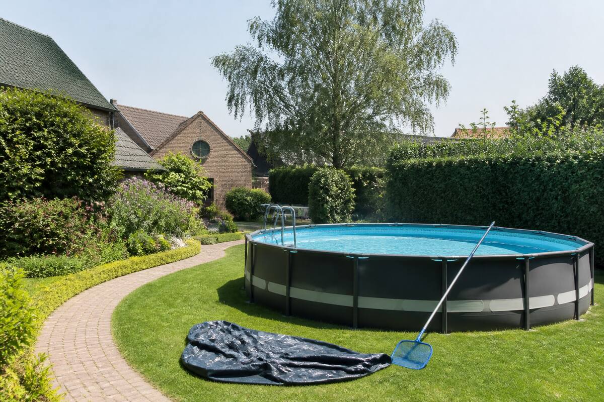Opzetzwembad in een verzorgde tuin met onderhoudsmateriaal ernaast