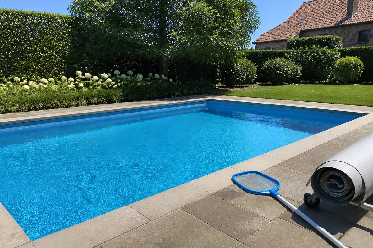 Helder zwembad in een tuin met onderhoudsmateriaal naast het water